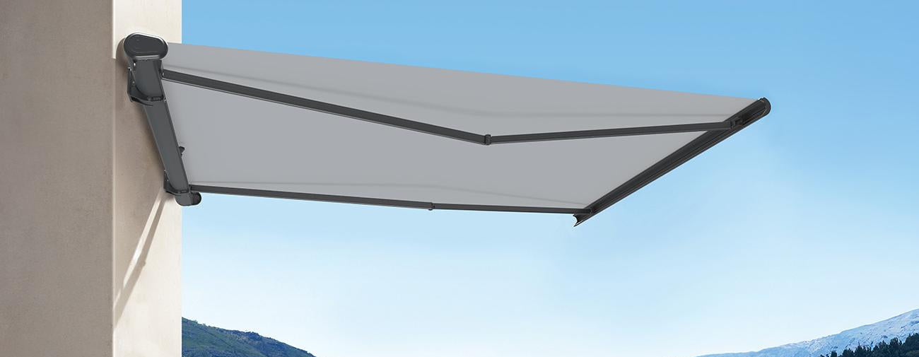 Outdoor patio setup with a retractable awning, chairs, and a table with a scenic background.